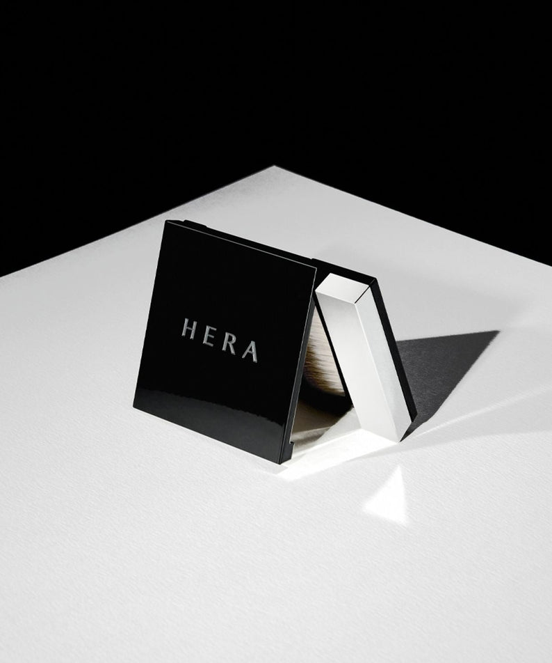 HERA Airy Powder Primer 8.5g compact showcased on a white surface, featuring sleek black packaging ideal for a flawless makeup base.