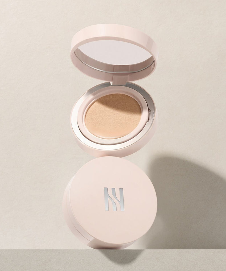 HERA Reflection Skin Glow Cushion Foundation 15g open on beige background, showcasing the product design and compact size.