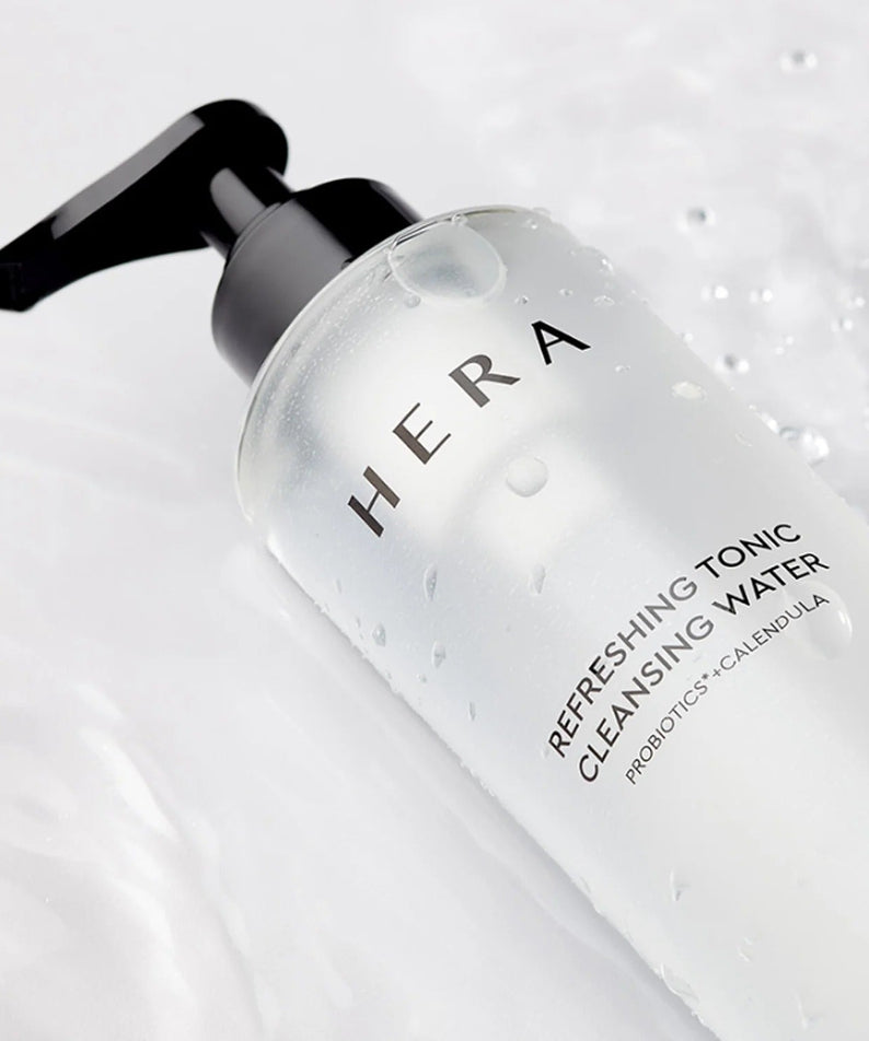 HERA Refreshing Tonic Cleansing Water 200ml bottle on a white surface with water droplets.