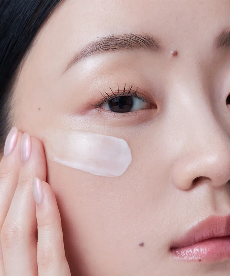 Woman applying HERA Rejuvanate Ampoule Cream 50ml on cheek for skincare