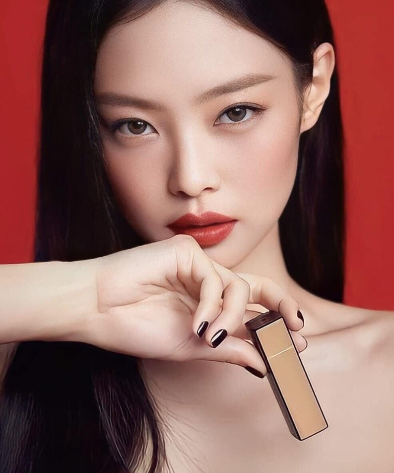 Model holding HERA Rouge Clasyy 3.5g lipstick with bold red color against a red background.
