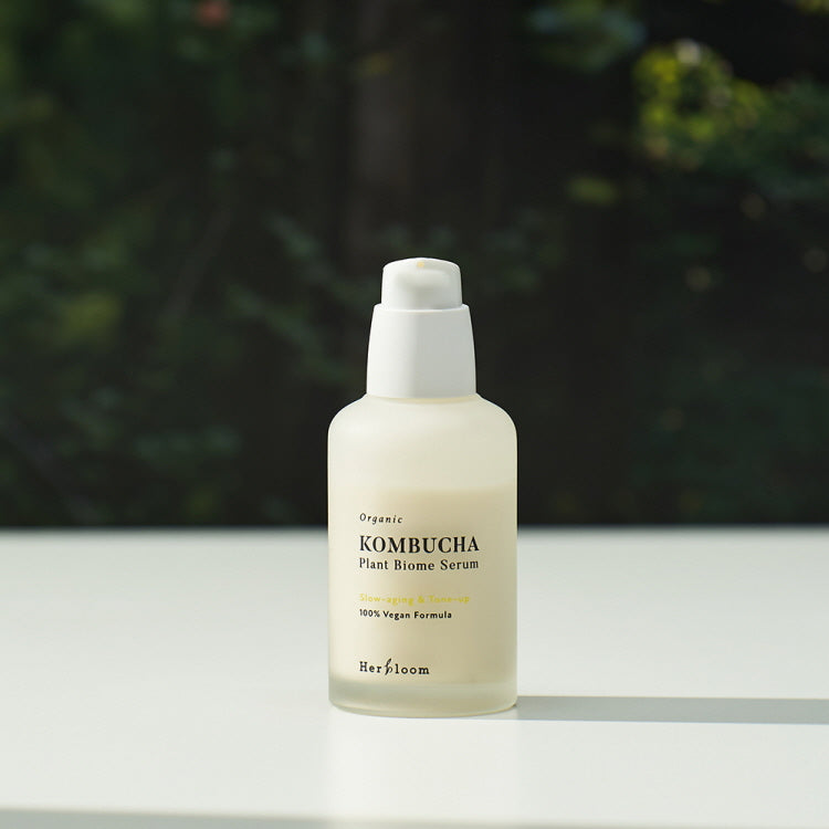 Bottle of HERBLOOM Organic Kombucha Plant Biome Serum 50ml on a table with nature background.