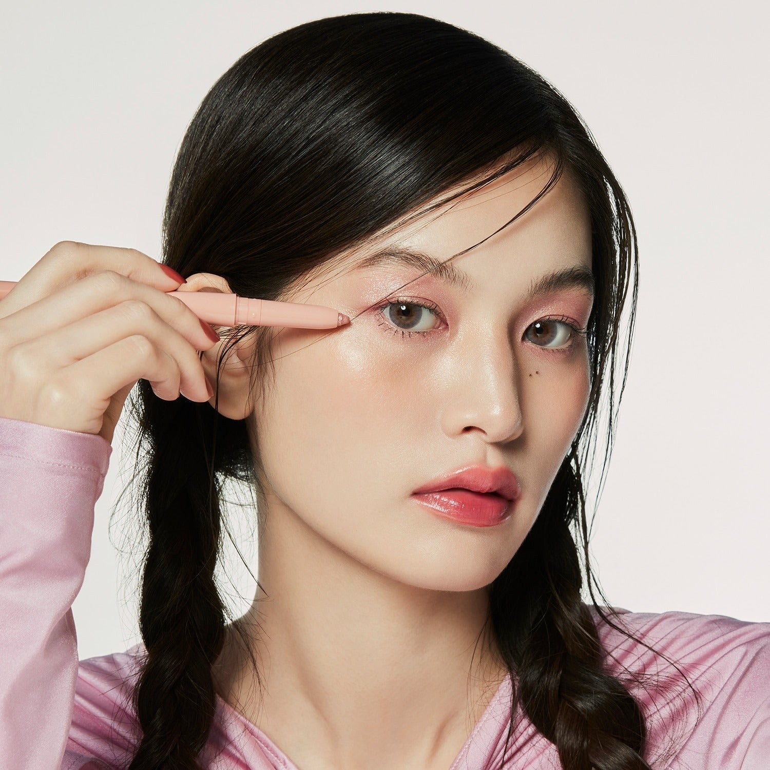 Model applying HINCE Depth Dual Color Stick on eyelids, showcasing vibrant makeup look.