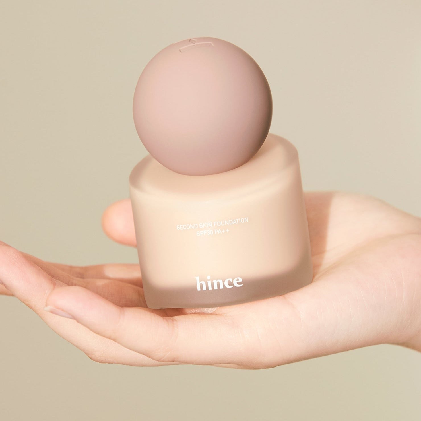HINCE Second Skin Foundation in hand, showcasing smooth texture and elegant packaging.