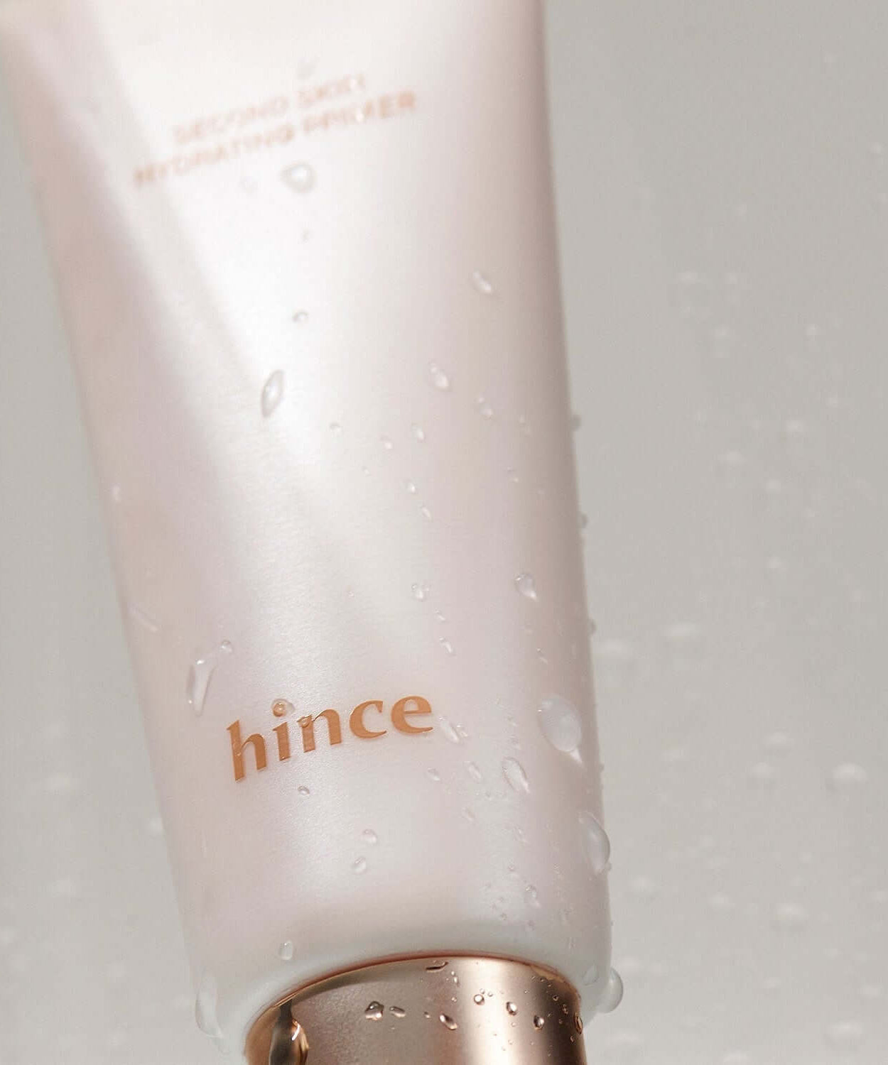 HINCE Second Skin Hydrating Primer with water droplets on the packaging, showcasing sleek and radiant design for flawless skin application.