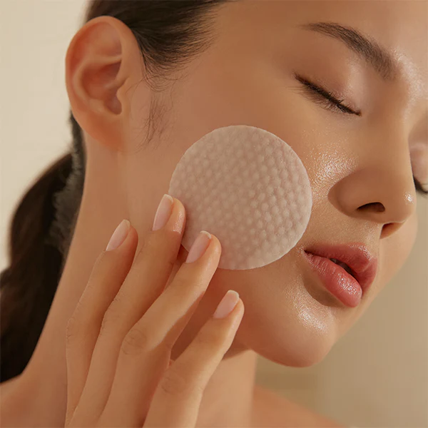 Woman using HOLITUAL Radiance Resurfacing Peel on her face for skincare routine