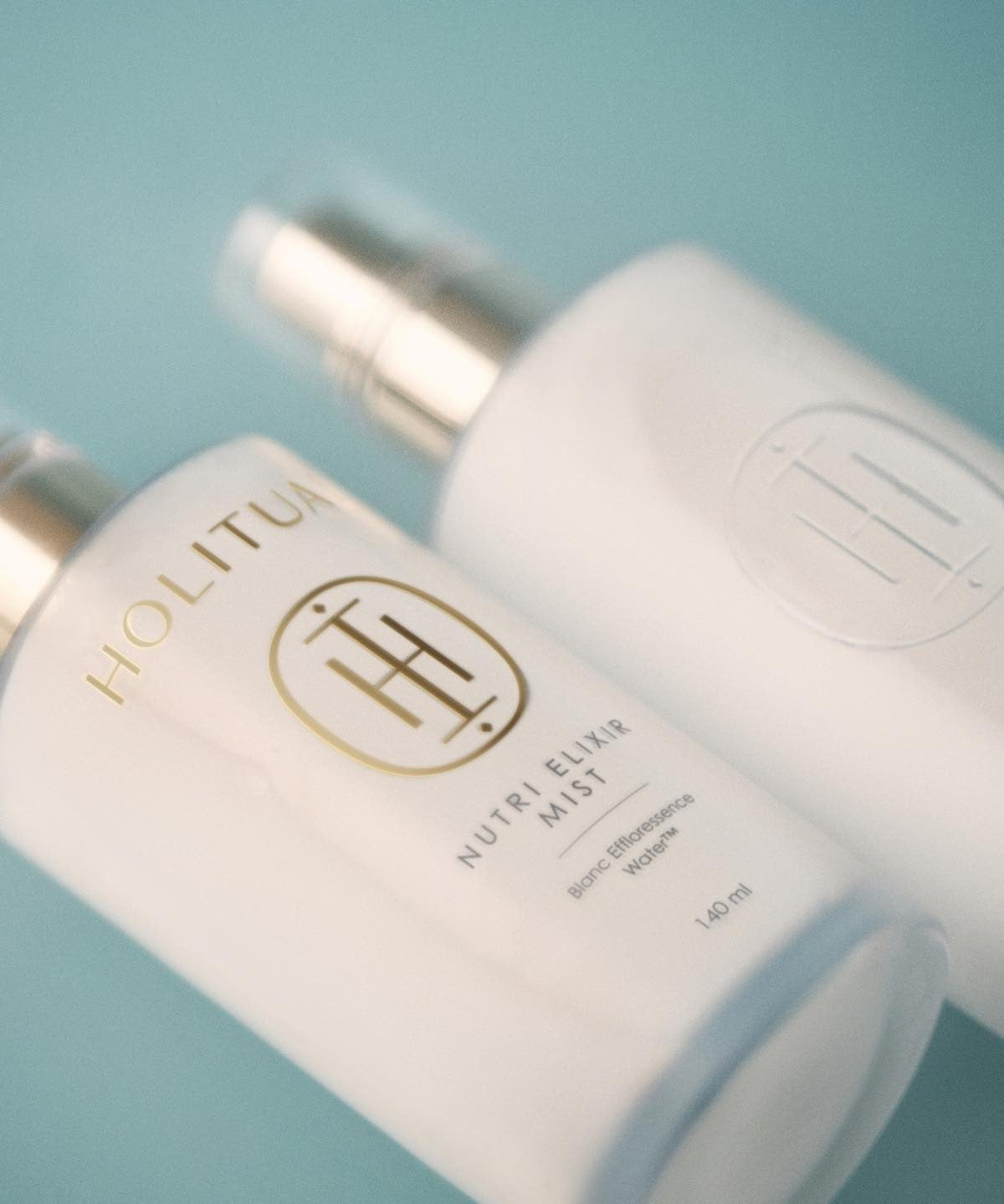 HOLITUAL Elixir Mist 140ml bottles on a teal background