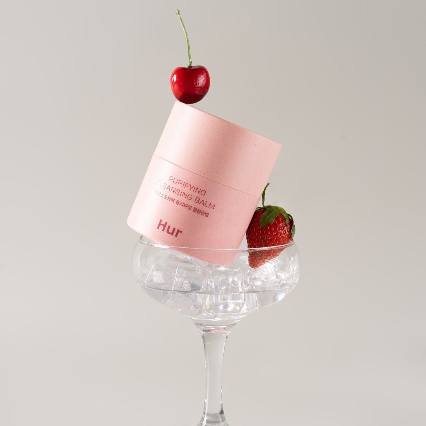 HOUSE OF HUR Purifying Cleansing Balm displayed with cherry and strawberry in a glass.