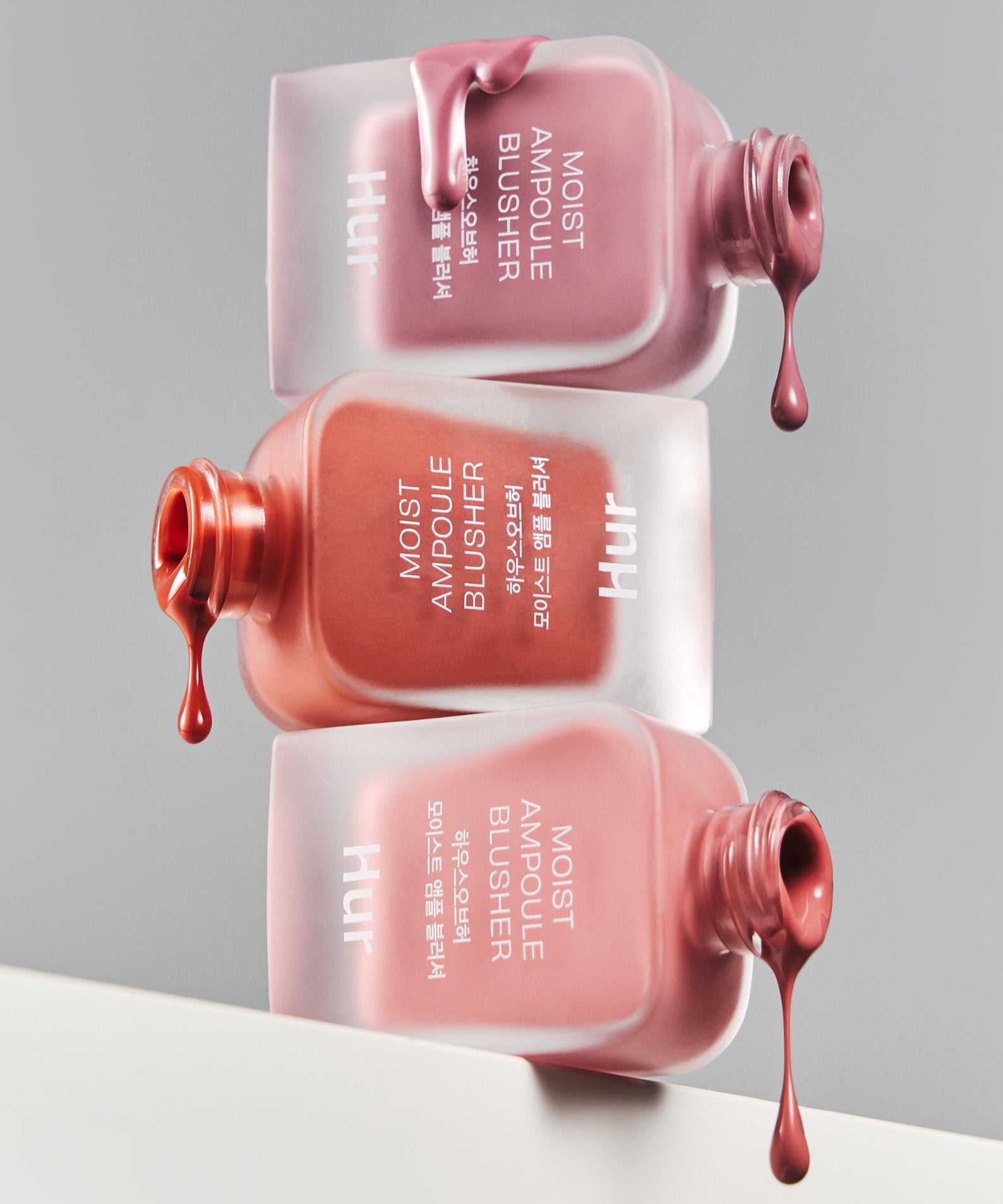 HOUSE OF HUR Moist Ampoule Blusher 10ml bottles with rich, creamy texture in assorted shades spilling artistically on a reflective surface.