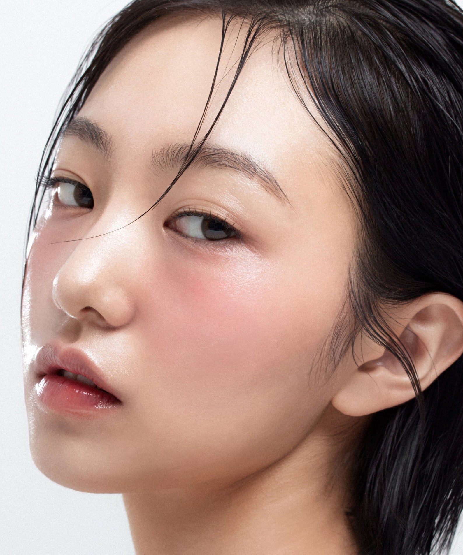 Close-up of model wearing HOUSE OF HUR Moist Ampoule Blusher 10ml on cheeks, showcasing natural glow and dewy finish.