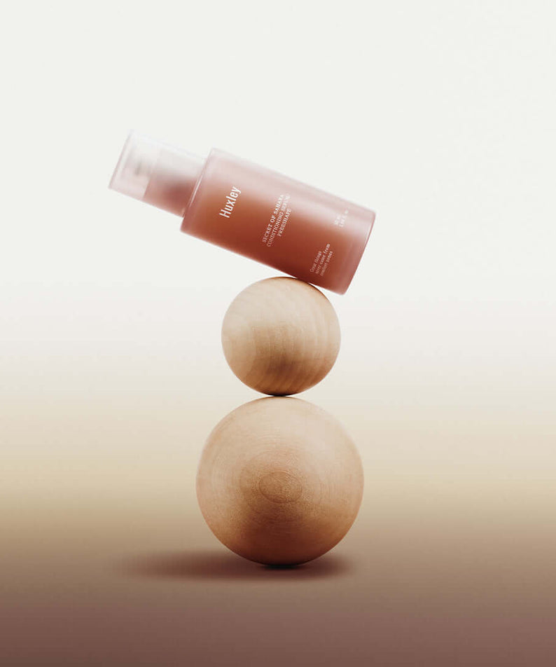 HUXLEY Conditioning Serum Preshape bottle balancing on wooden spheres