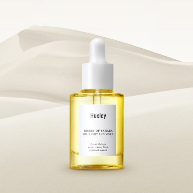 HUXLEY Oil Light and more 30ml bottle on sand background, showcasing skincare product.