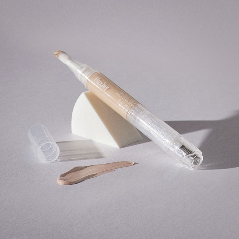 HUXLEY Relaxing Concealer Stay sun Safe displayed with makeup sponge and sample swatch