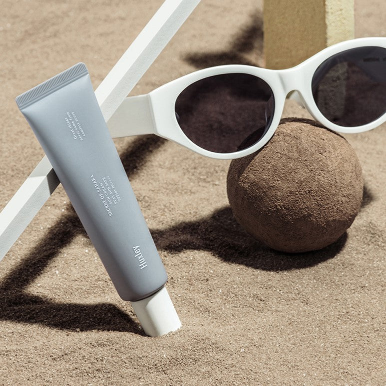 HUXLEY Sun Cream Stay Sun Safe SPF50+ PA++++ 30ml on sandy beach with sunglasses