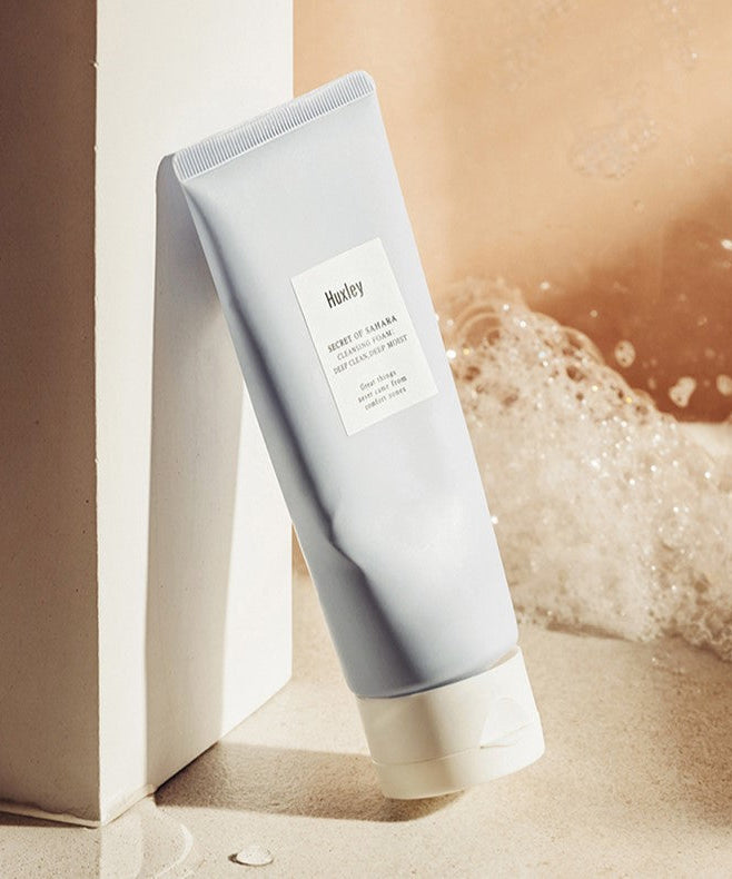 HUXLEY Cleansing Foam Deep Clean Deep Moist 150g in a bathroom setting with bubbles in the background.