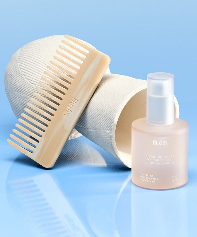 HUXLEY Hair Oil Essence Moroccan Gardener 50ml with comb, perfect for nourishing and styling hair, on a blue background.