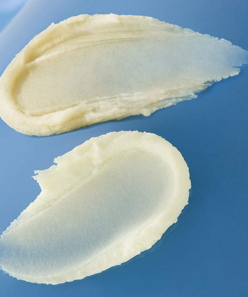 Texture of HUXLEY Sun Stick Watery Touch 20g showing creamy application on a blue background.