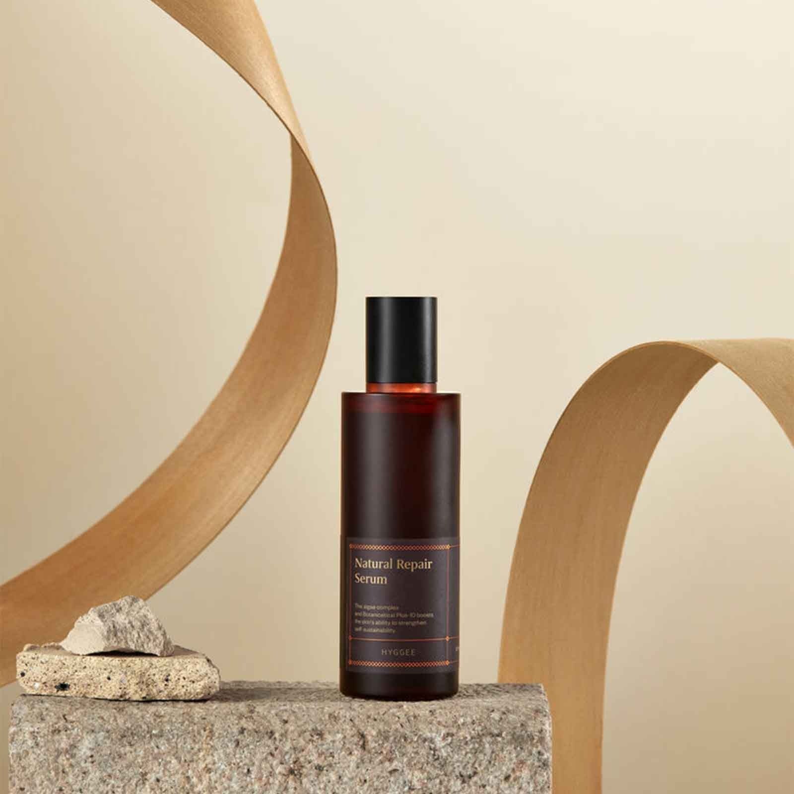 HYGGEE Natural Repair Serum 120ml bottle displayed on a textured stone with minimalist background