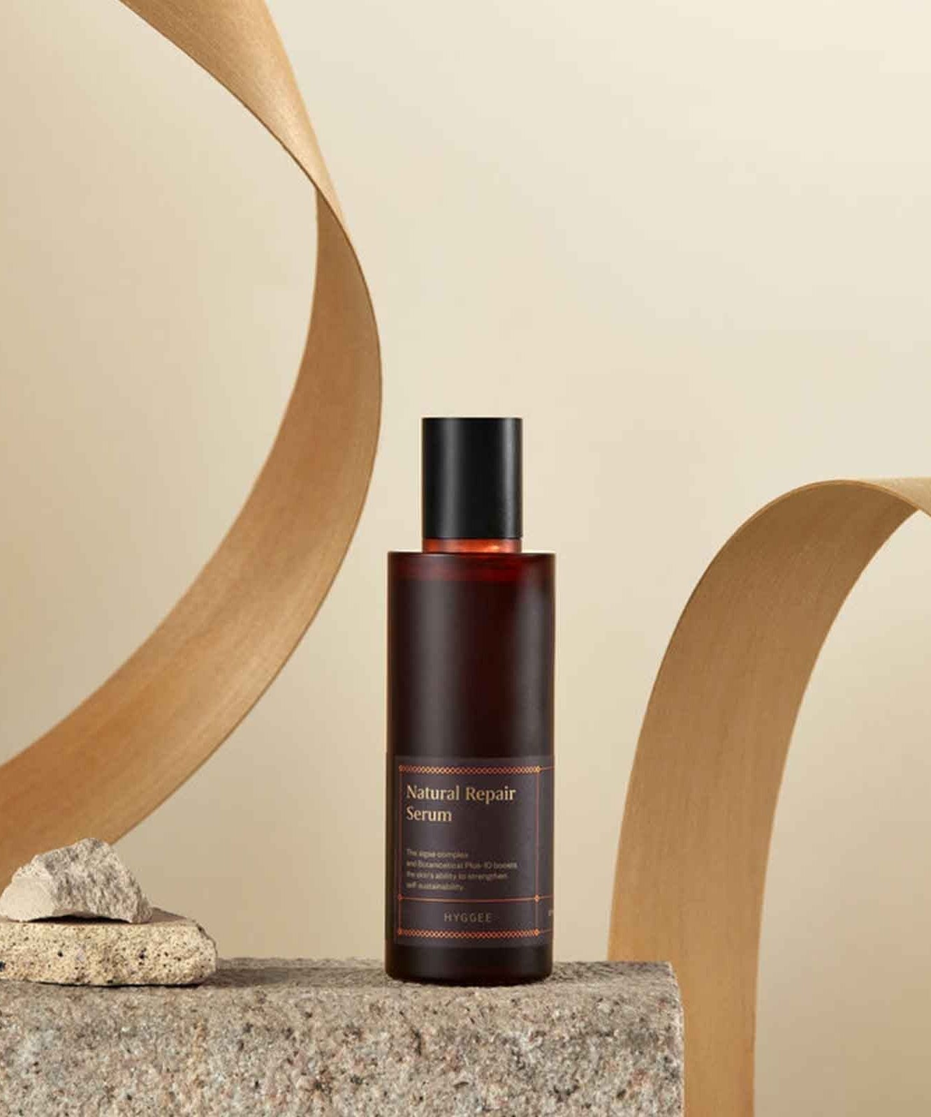 HYGGEE Natural Repair Serum 120ml bottle displayed on a textured stone with minimalist background