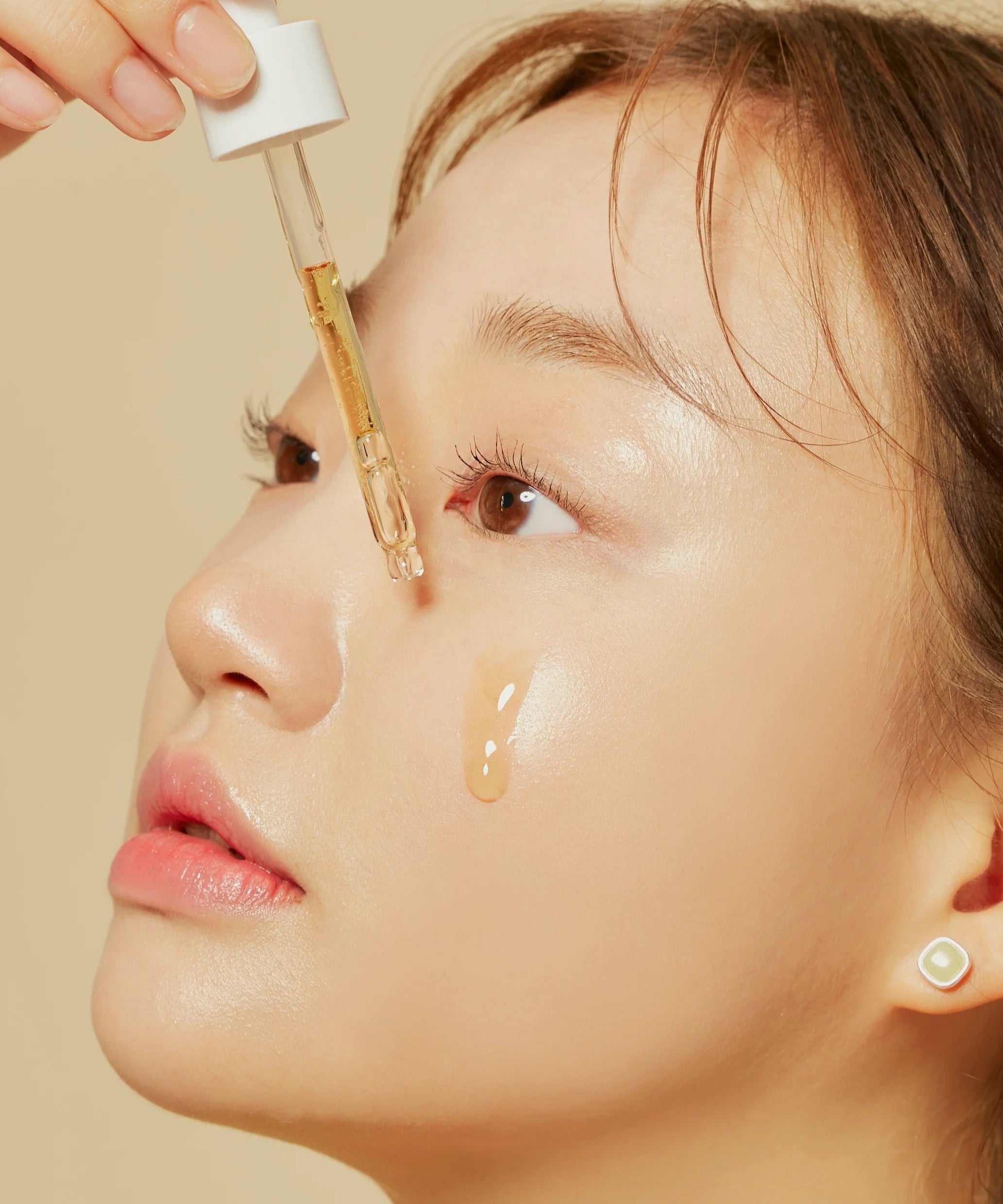 Woman applying HYGGEE Own Vegan Calming Serum 50ml to her face with dropper, showcasing skincare application and hydration.
