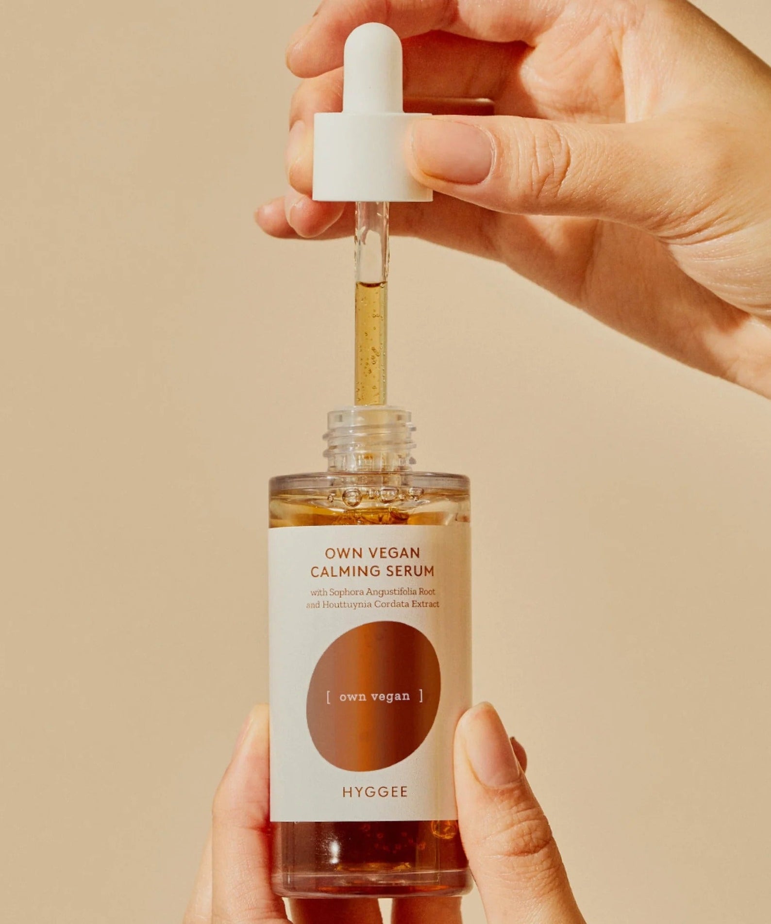 HYGGEE Own Vegan Calming Serum 50ml with dropper in hands against a neutral background.
