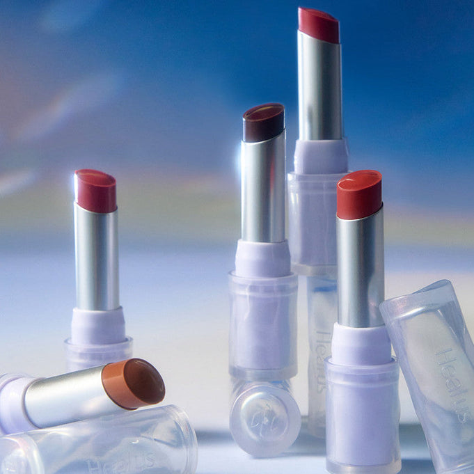 Collection of HEALUS Bare Lip Glow 4g lipsticks in various shades arranged against a soft, blurred background.