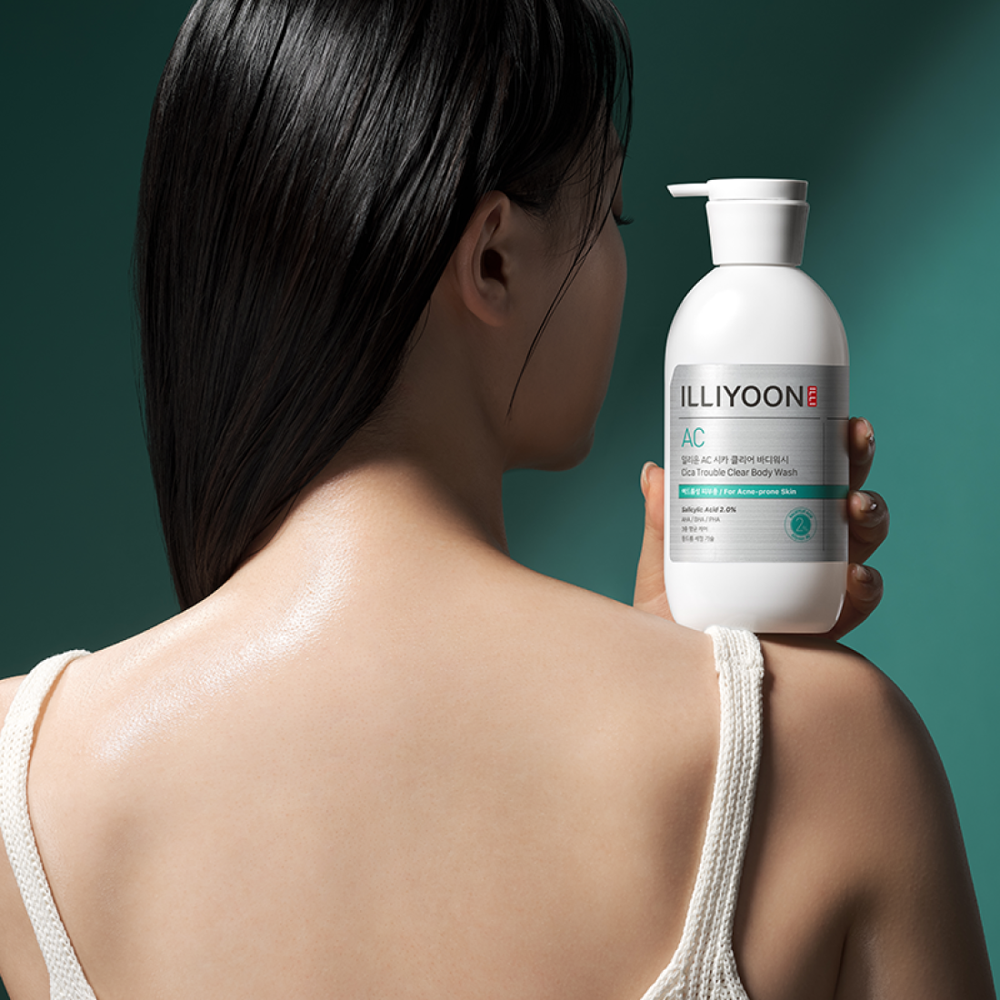 Woman holding ILLIYOON Cica Acne Clear Body Wash 400ml bottle, showcasing smooth skin care benefits.