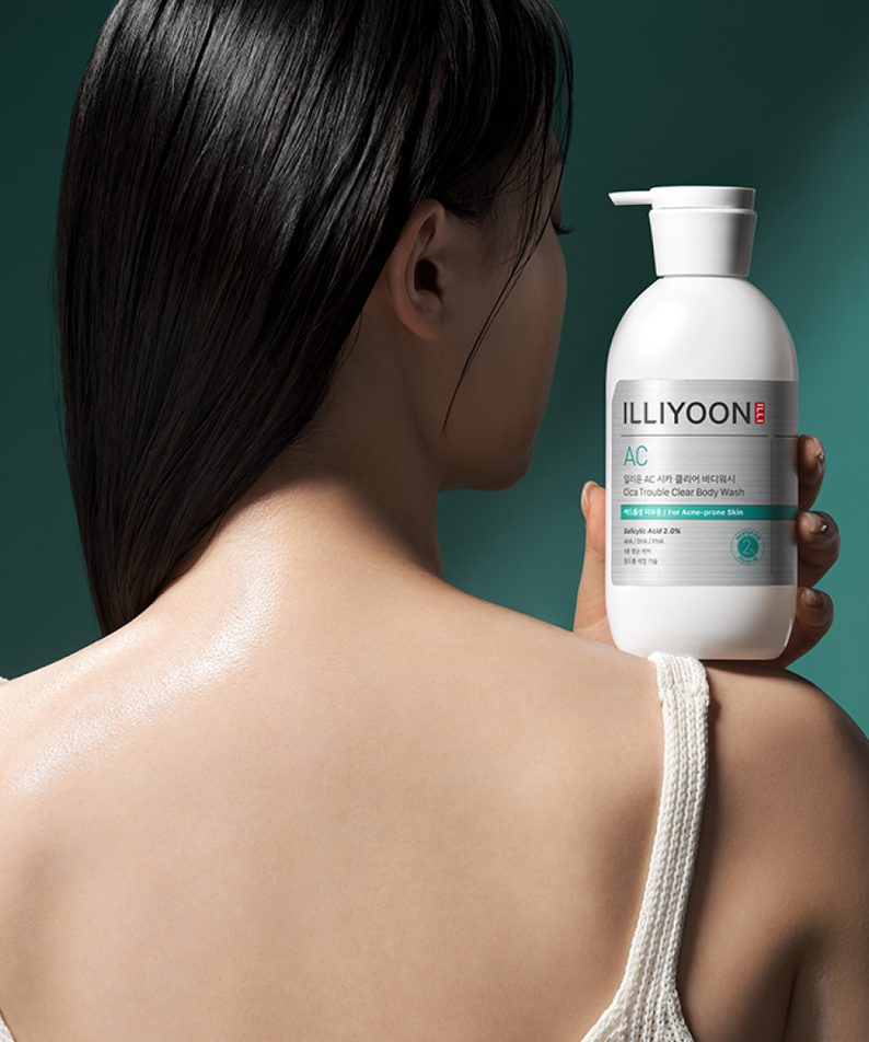 Woman holding ILLIYOON Cica Acne Clear Body Wash 400ml bottle, showcasing smooth skin care benefits.