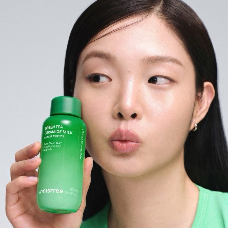 Person holding INNISFREE Green Tea Ceramide Milk Essence 160ml bottle close to face.