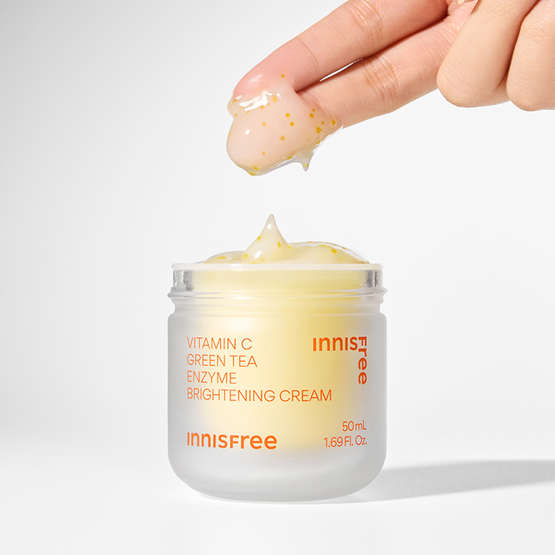 INNISFREE Vitamin C Enzyme Brightening Cream 50ml being applied with fingertips, showcasing texture and packaging.