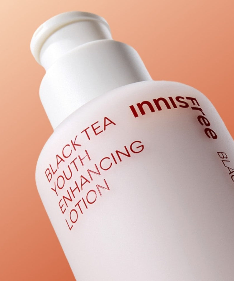 Bottle of INNISFREE Black Tea Youth Enhancing Lotion 170ml against an orange background