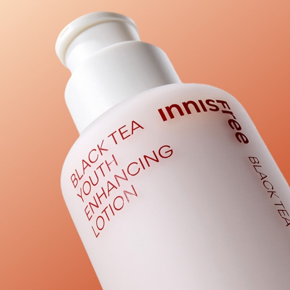 Bottle of INNISFREE Black Tea Youth Enhancing Lotion 170ml against an orange background