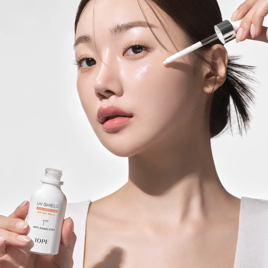 Woman applying IOPE UV Sheild Sun Ampoule SPF 50+PA+++ 40ml on her face for sun protection and skincare