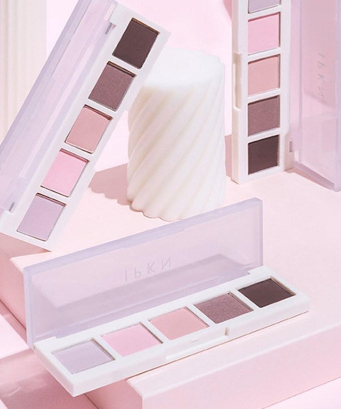 IPKN Personal Mood Palette Plain Summer & Winter 5g with soft pastel eyeshadow colors in an open case on a pink background.