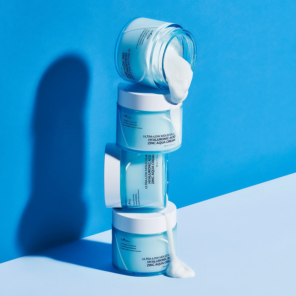 Stacked jars of ISNTREE Hyaluronic Acid ZINC Moisture Cream 80ml against a blue background