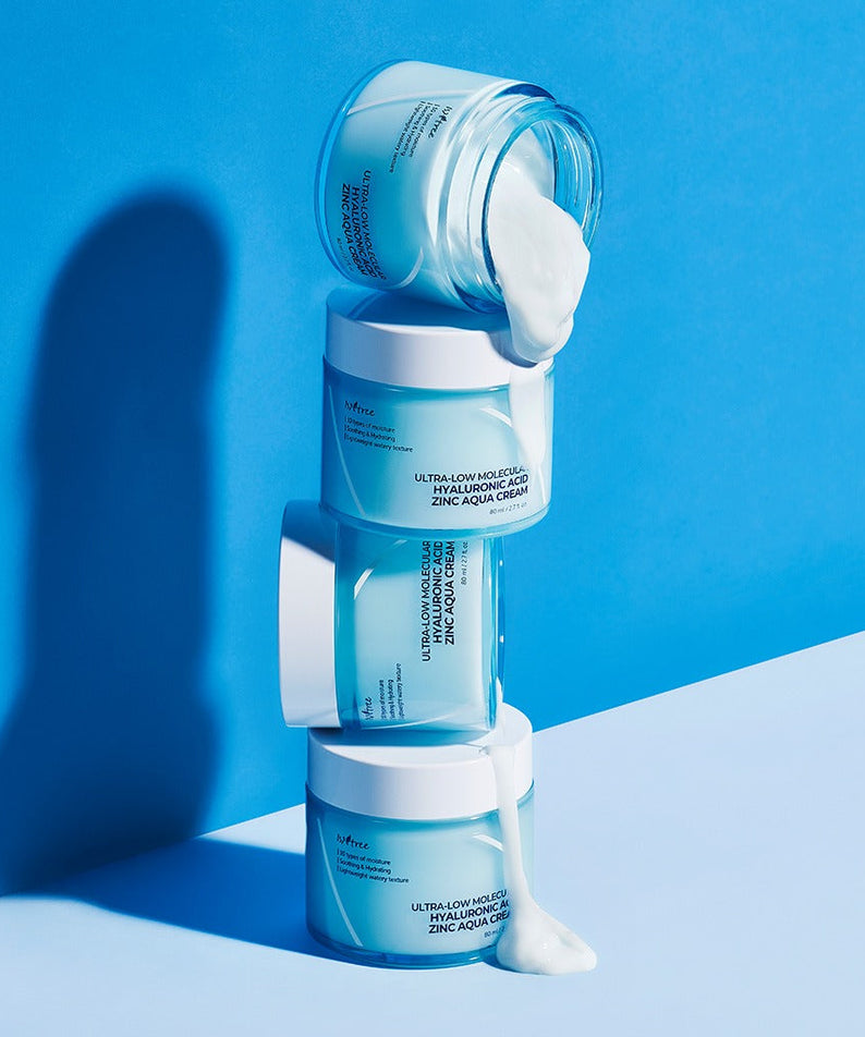 Stacked jars of ISNTREE Hyaluronic Acid ZINC Moisture Cream 80ml against a blue background
