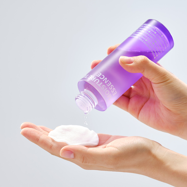 ISOI Moisture Tonic Essence 130ml being poured onto a cotton pad, showcasing the product's application method.