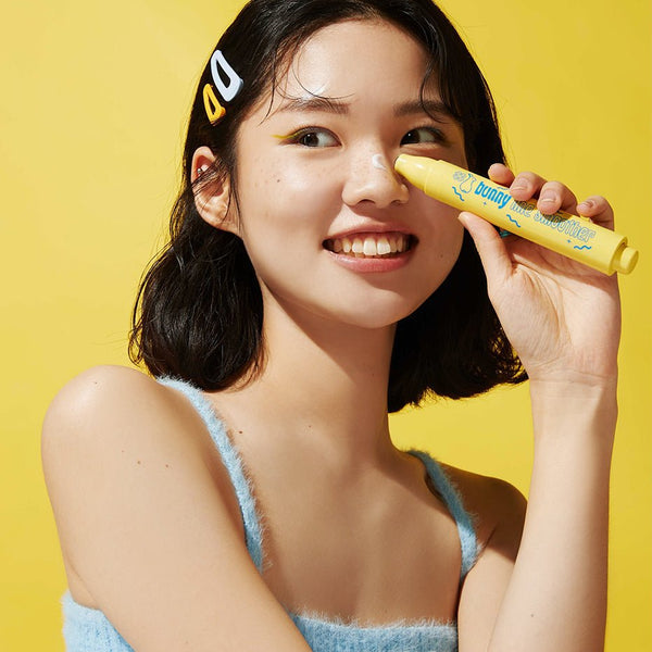 Smiling person holding IT'S SKIN Bunny Line Smoother against a yellow backdrop