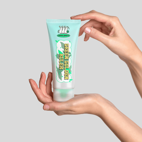 Hands holding IT'S SKIN Green Golden Ruler Cream in a turquoise tube