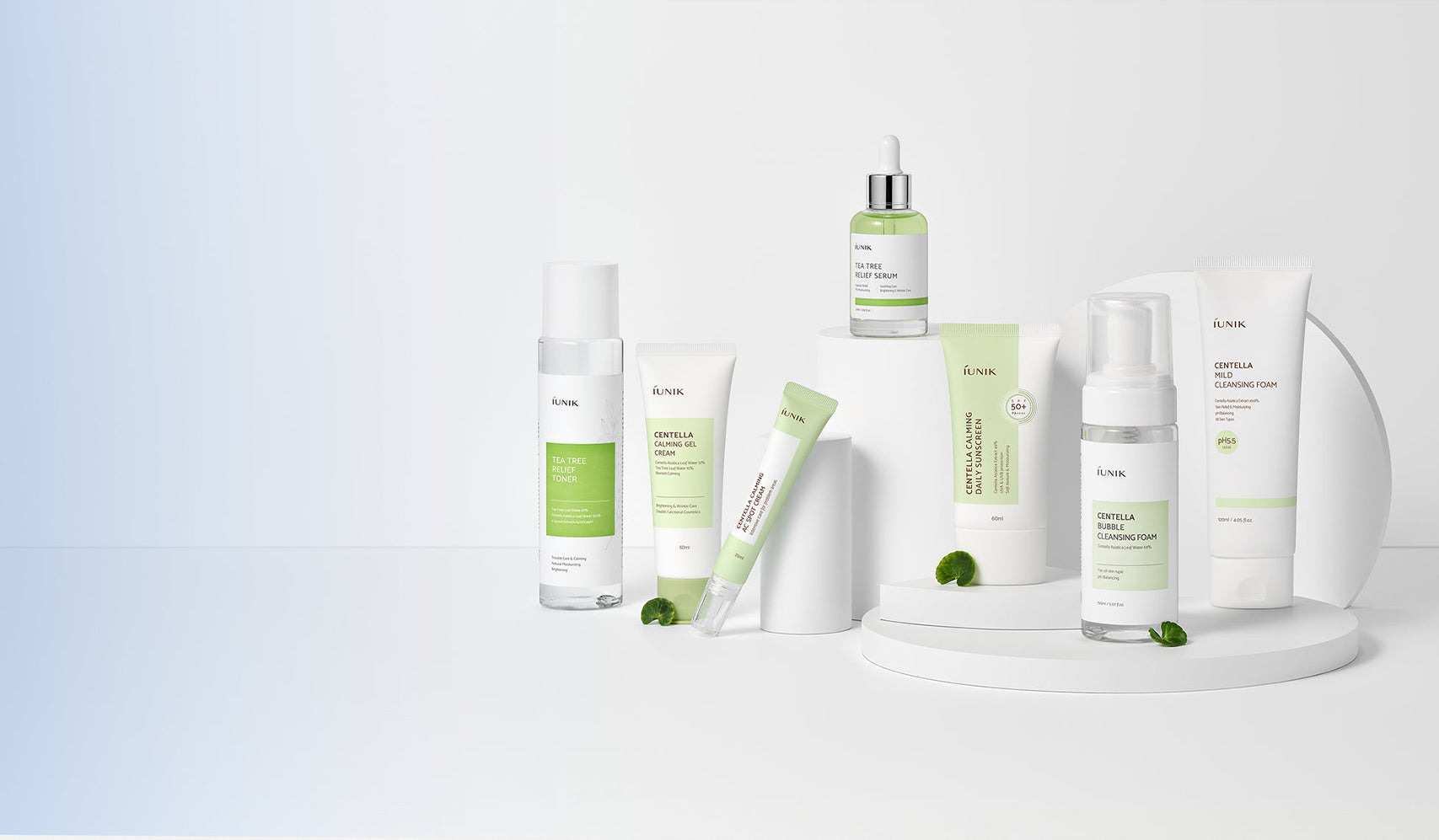 Assorted skincare products with green packaging displayed on a white surface and stand, minimalist design aesthetic.