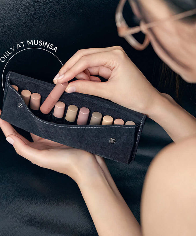 Close-up of a makeup pouch with several nude lipsticks being unzipped, available exclusively at Musinsa.