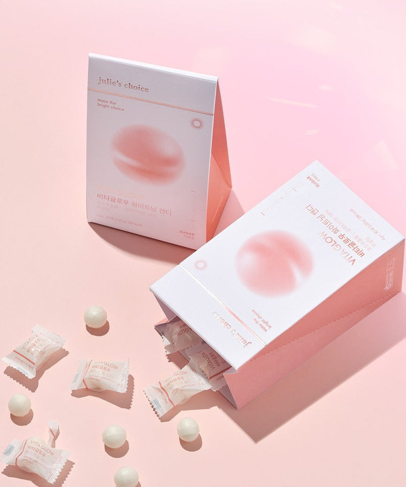 JULIE'S CHOICE Vita Glow Whitening Candy packaging with scattered candies on a pink background.