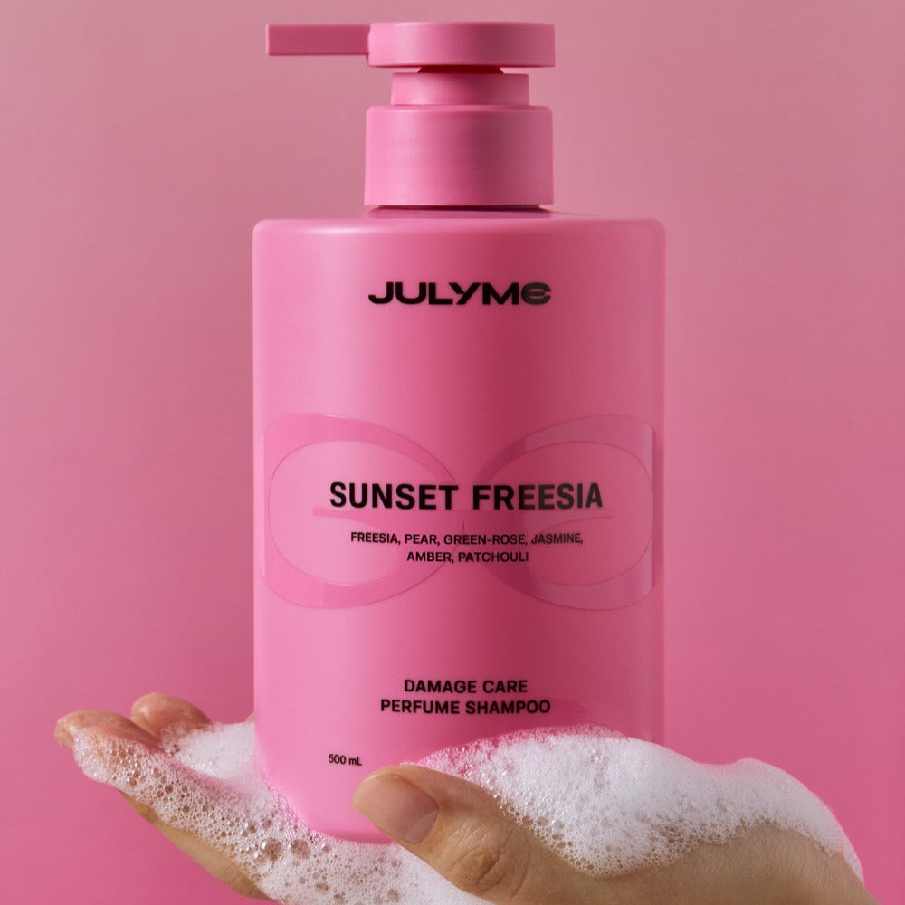 JULYME Damage Care Perfume Hair Shampoo 500ml in hand with pump dispenser, pink bottle showing sunset freesia label.