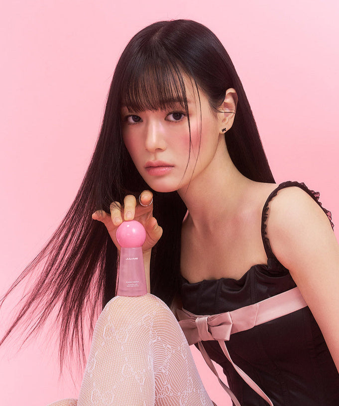 Model holding JULYME Damage Care Perfume Hair Oil 30ml (Sunset Freesia) against pink background