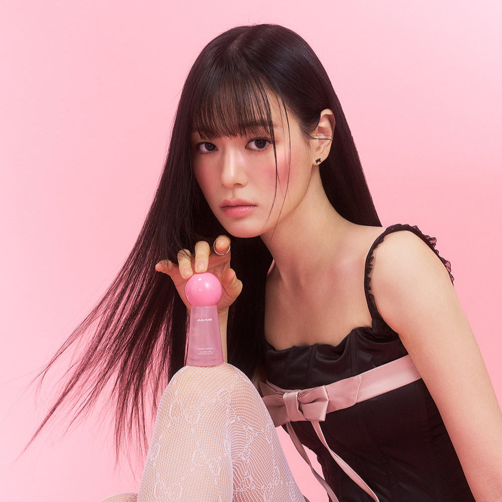 Model holding JULYME Damage Care Perfume Hair Oil 30ml (Sunset Freesia) against pink background