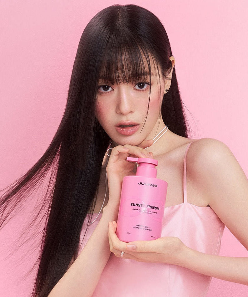 Woman holding JULYME Damage Care Perfume Hair Shampoo 500ml bottle in pink dress with pink background.