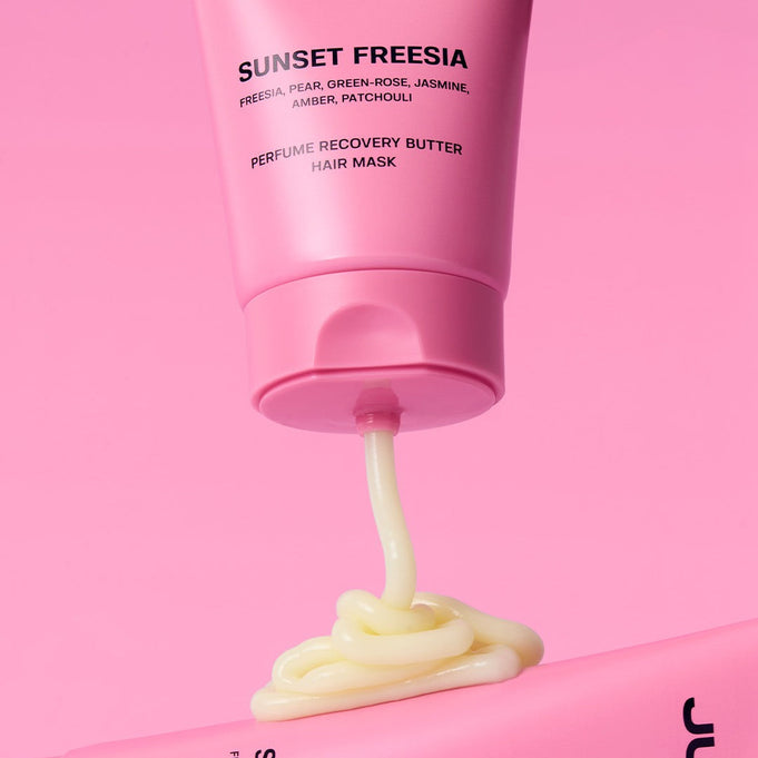 SUNSET FREESIA Perfume Recovery Butter Hair Mask with freesia, pear, and patchouli in bright pink tube on pink background.
