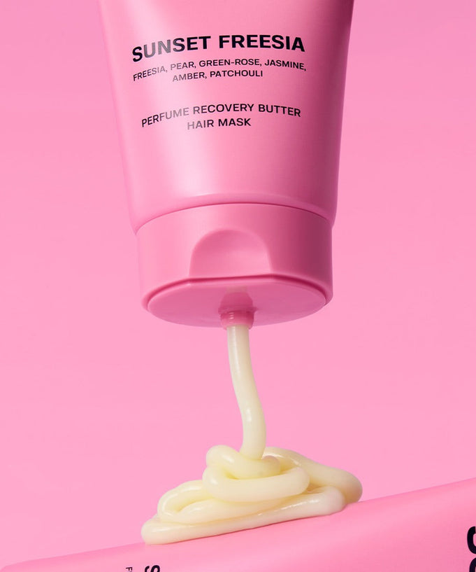 SUNSET FREESIA Perfume Recovery Butter Hair Mask with freesia, pear, and patchouli in bright pink tube on pink background.