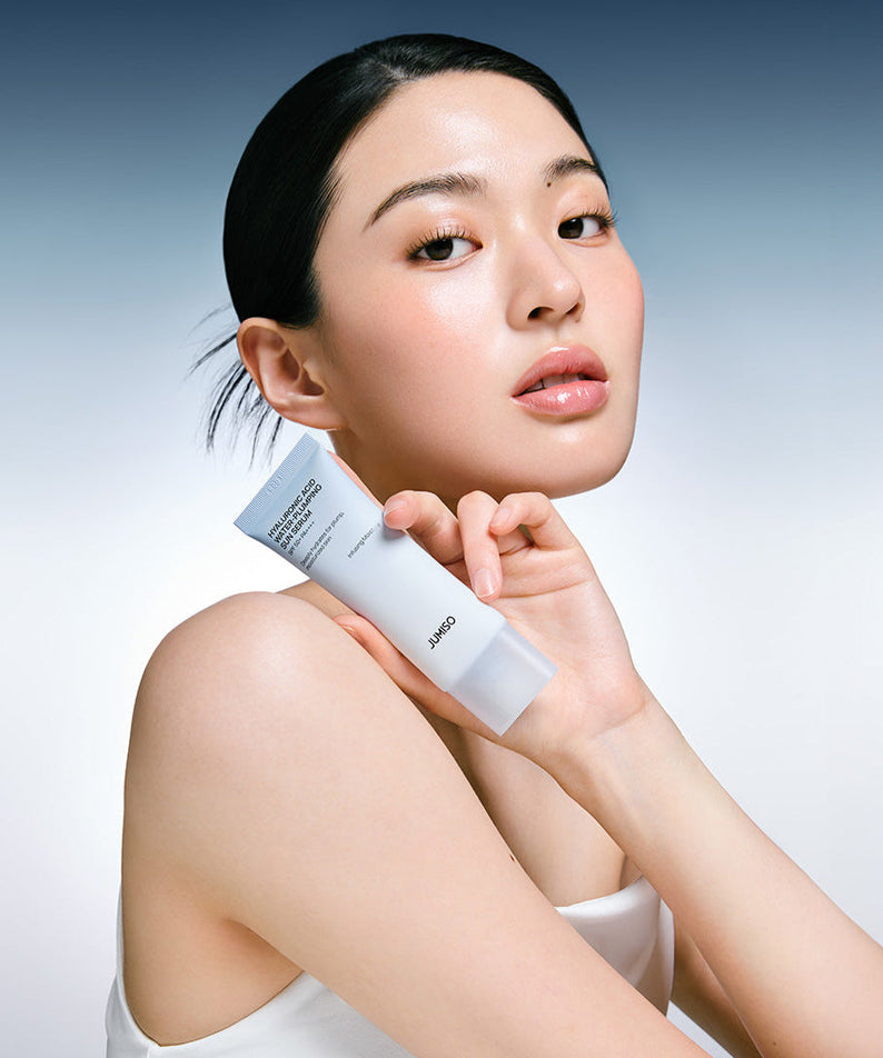 Model holding JUMISO Hyaluronic Acid Water Plumping Moisture Sun Serum 40ml against gradient background