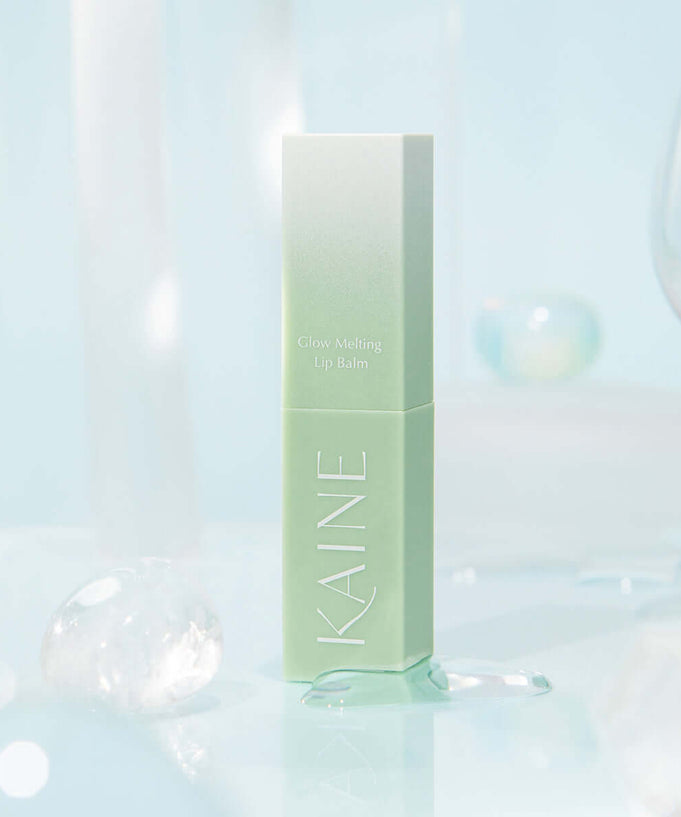 KAINE Glow Melting Lip Balm in pastel green packaging on a light blue background.